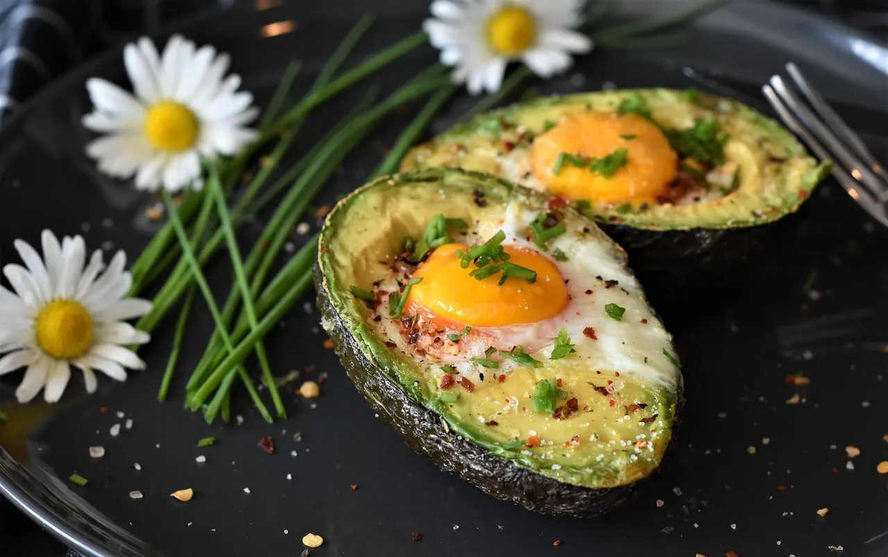 Huevos horneados en mitades de aguacate sobre un plato oscuro — un desayuno que supera los 25 gramos de proteína